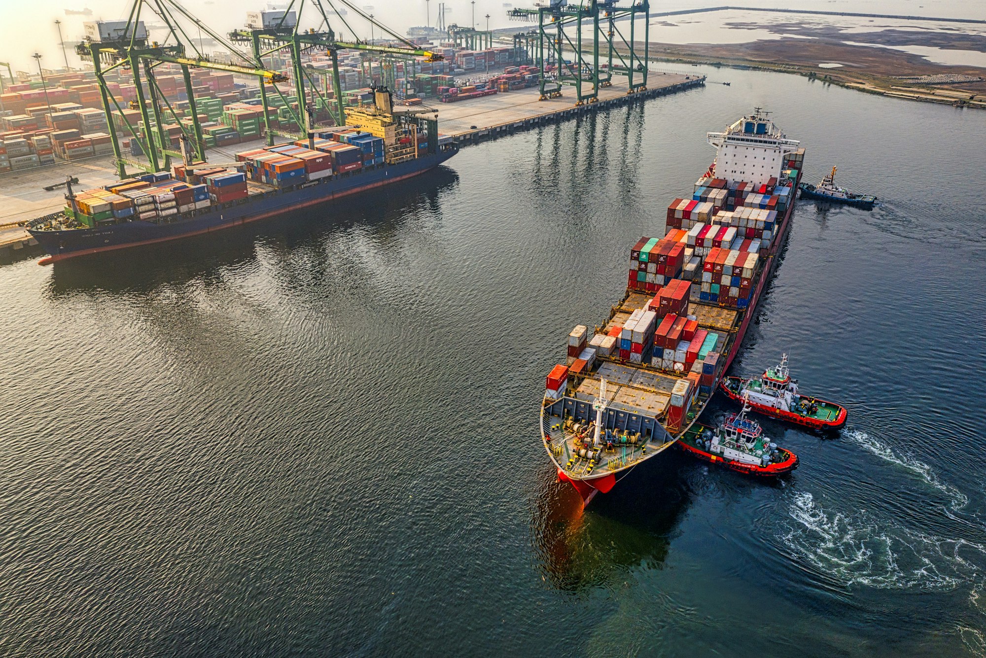 Container ship docked at a port, being loaded by gantry cranes